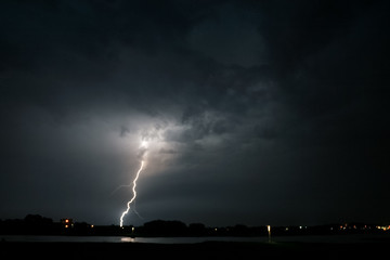Wall Mural - a lightning bolt strikes down from a severe thunderstorm near the river waal in the netherlands. pho