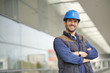 © goodluz - Smiling industrial worker in hardhat infront of modern building