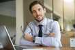 © goodluz - Smart handsome businessman in office with laptop looking at camera