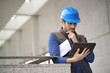 © goodluz - Handsome building expert in hardhat outdoors with tablet and blueprint