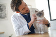 © goodluz - Handsome vet looking at beautiful cat in vetinarian clinic