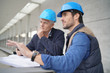 © goodluz - Workmen consulting over blueprint on modern building sight