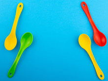 Yellow Red And Green Plastic Spoons On Blue Background With Copy Space For Text