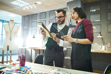 Portrait of two contemporary designers discussing sketches while working on creative project together in luxury jewelry workshop, copy space