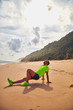 © astrosystem - Sportsman stretching on a exotic tropical beach after jogging / exercising.