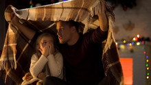 Father Telling Horror Christmas Story For Little Girl Sitting Under Cozy Plaid