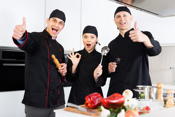 Three young cooks wearing black uniform showing thumbs up