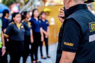 head of security guard call meeting and talk into walkie talkie for communication to the team.