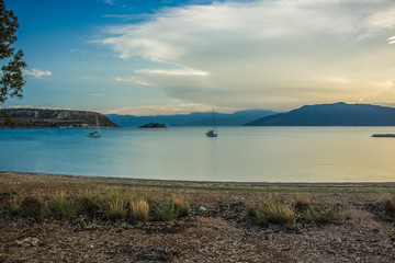 Wall Mural - evening calm sea bay beautiful nature scenery landscape surrounded mountain horizon background and small boat on water surface