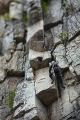 Wall Mural - Woman climber on the background of a steep rock wall. Tilt-Shift effect.