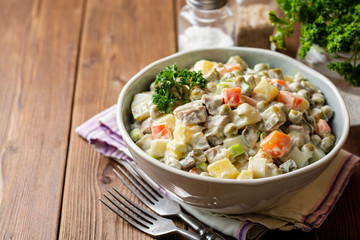 Wall Mural - Traditional Russian salad Olivier in bowl on wooden table. Selective focus.