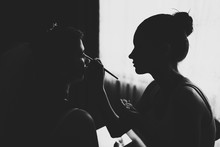 Makeup Artist Doing Makeup For The Bride.  Morning Of Wedding Day. Black And White Photo Against The Window