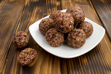 Wall Mural - Energy balls with dried cranberry in the white plate on the brown wooden background