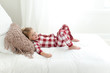 © Samantha McBride - Young smiling girl wearing pajamas lying down on a bed