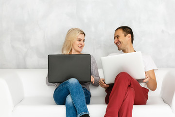 Wall Mural - Young couple relaxing on sofa with digital two laptop.