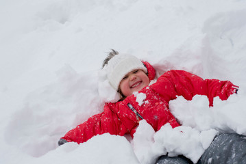 Adorable girl lying on his back in the snow and having fun 