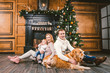 © Elizaveta - Theme Christmas and New Year family circle. Young Caucasian family with 1 year old child dog breed Labrador Golden Retriever sitting on wooden floor home in living room near fireplace Christmas tree