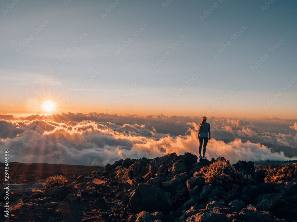 a girl with wanderlust standing on Haleakalā and watching the sunset - obrazy, fototapety, plakaty 