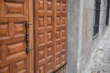 Closeup of a locked and closed wooden door is seen on this picture. The design on the door can be seen clearly. It seems the brown colored door is old.