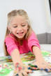 © W PRODUCTION - portrait of a beautiful young kid girl painting on a white paper with color paint at home