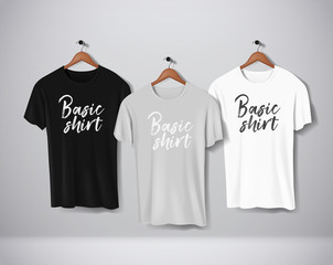 basic black, gray and white short sleeve t-shirts mock-up clothes set hanging isolated on wall. fron