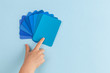 Child's hand pointing at color samples cards - hues of blue with copy space