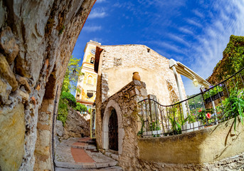 Old traditional architecture of Eze village, historic tower of church and the main entrance gate of the town in France