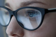 © aleksmark2016 - Close-up shot of woman eyes in glasses reflecting a working computer