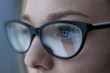 © aleksmark2016 - Close-up shot of woman eyes in glasses reflecting a working computer