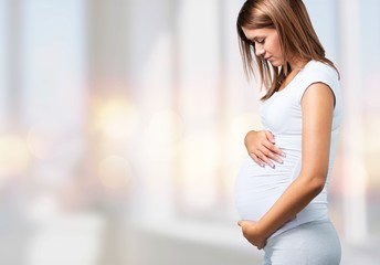 Canvas Print - Pregnant young woman in white t shirt on  background