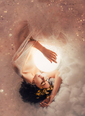 gentle image of angel sleeping next to the moon in pink light clouds, naked body of slim girl lying 
