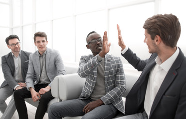 business colleagues giving each other a high five while sitting in the office lobby.