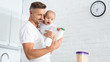 © LIGHTFIELD STUDIOS - father holding baby daughter and showing bottle with milk
