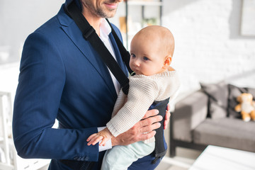 Wall Mural - cropped view of father holding infant daughter in baby carrier