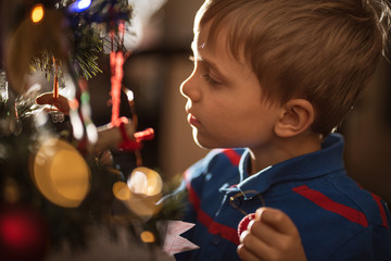 Portrait of 6 years old boy decorating Christmas tree