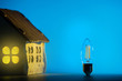 Silhouette led lamp against layout of the house on a blue background