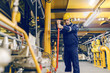 © dusanpetkovic1 - Young Caucasian worker in protective suit tightening the valve while standing in heating plant.