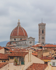 Florence Cathedral and Giotto's Bell Tower, under overcast sky, over houses of the historical center of Florence, Italy