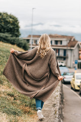 Wall Mural - outdoor portrait of fashion woman wearing long beige cardigan, back view