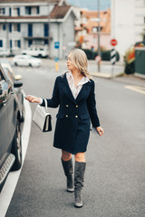 Wall Mural - beautiful businesswoman coming out of the car, wearing stylish blue dress