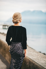 Wall Mural - outdoor portrait of beautiful woman wearing black velvet and sequin dress, posing next to lake, back