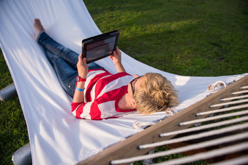 Sticker - woman using a tablet computer while relaxing on hammock