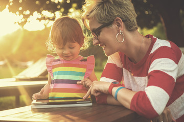 Sticker - mom and her little daughter using tablet computer