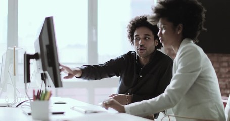 Coworkers looking at a desktop computer together