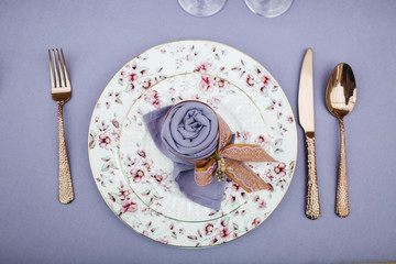 Wall Mural - Dinner table serving. Violet and beige tones, pastel colors. Beautiful decoration of wedding banquet in restaurant with glasses, plates, forks and knives, white tablecloth.