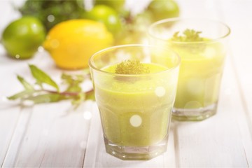 Wall Mural - Green vegetable smoothies in glasses on wooden table