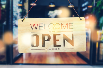 A business sign that says ‘Open’ on cafe or restaurant hang on door at entrance. Vintage color tone style.