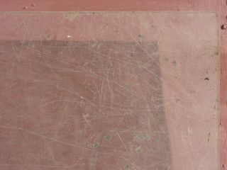 Glass texture with transparent scratched worn surface and pale red background 