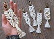 Hand made cotton macrame key chain close up with four blurred in the background that have different styles and some have beads. The background is a beautiful wooden floor.