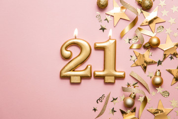 Number 21 gold celebration candle on star and glitter background